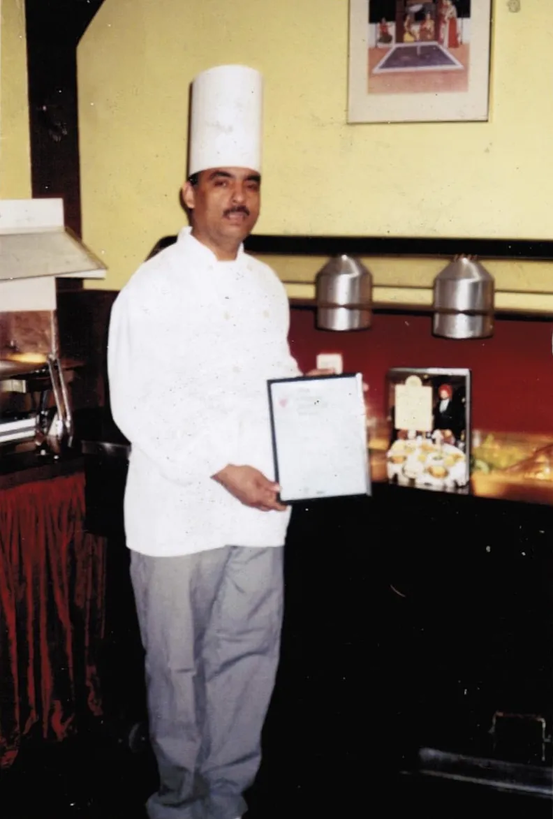 Archive photo of a chef holding a certificate in a restaurant kitchen
