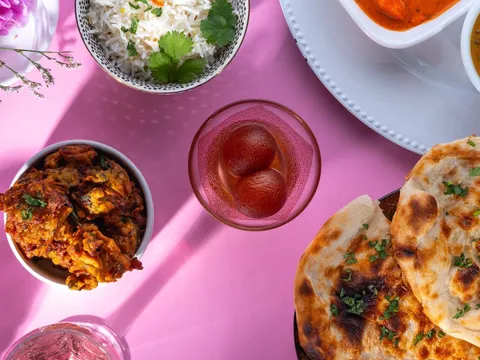 Overhead view of rice, pakoras, gulab jamun, butter chicken and naan